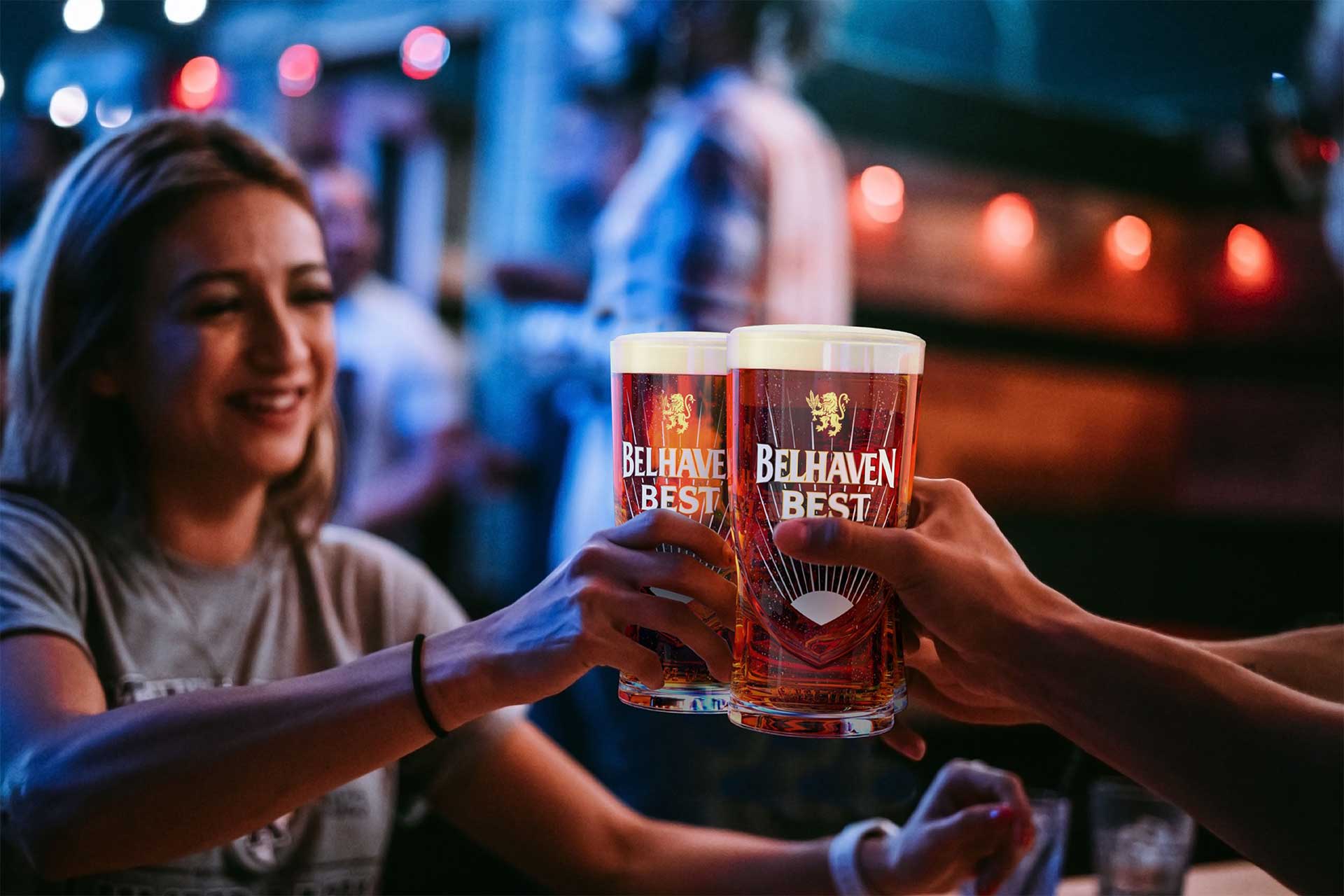 A woman cheering a pint of Belhaven Best with another person